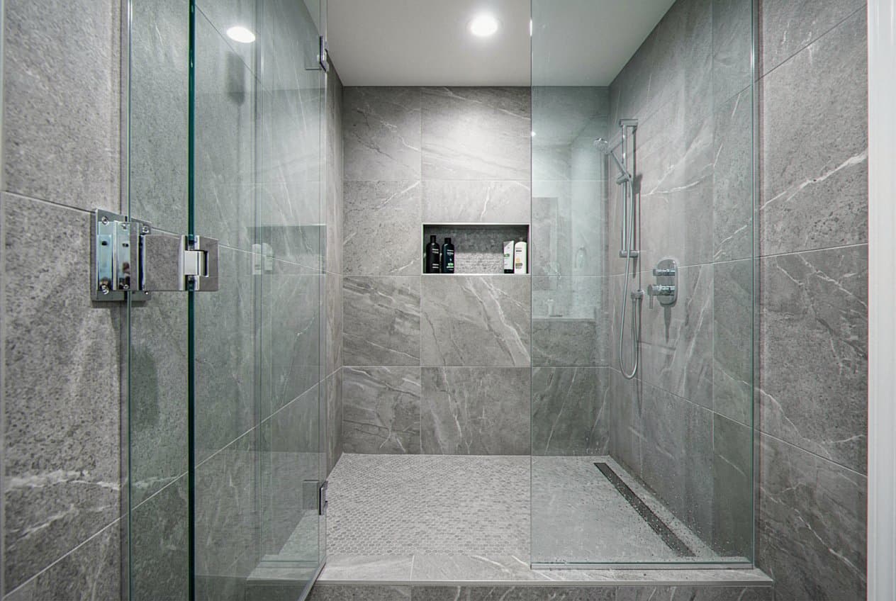 Stone-tiled shower with frameless glass and recessed shelf niche