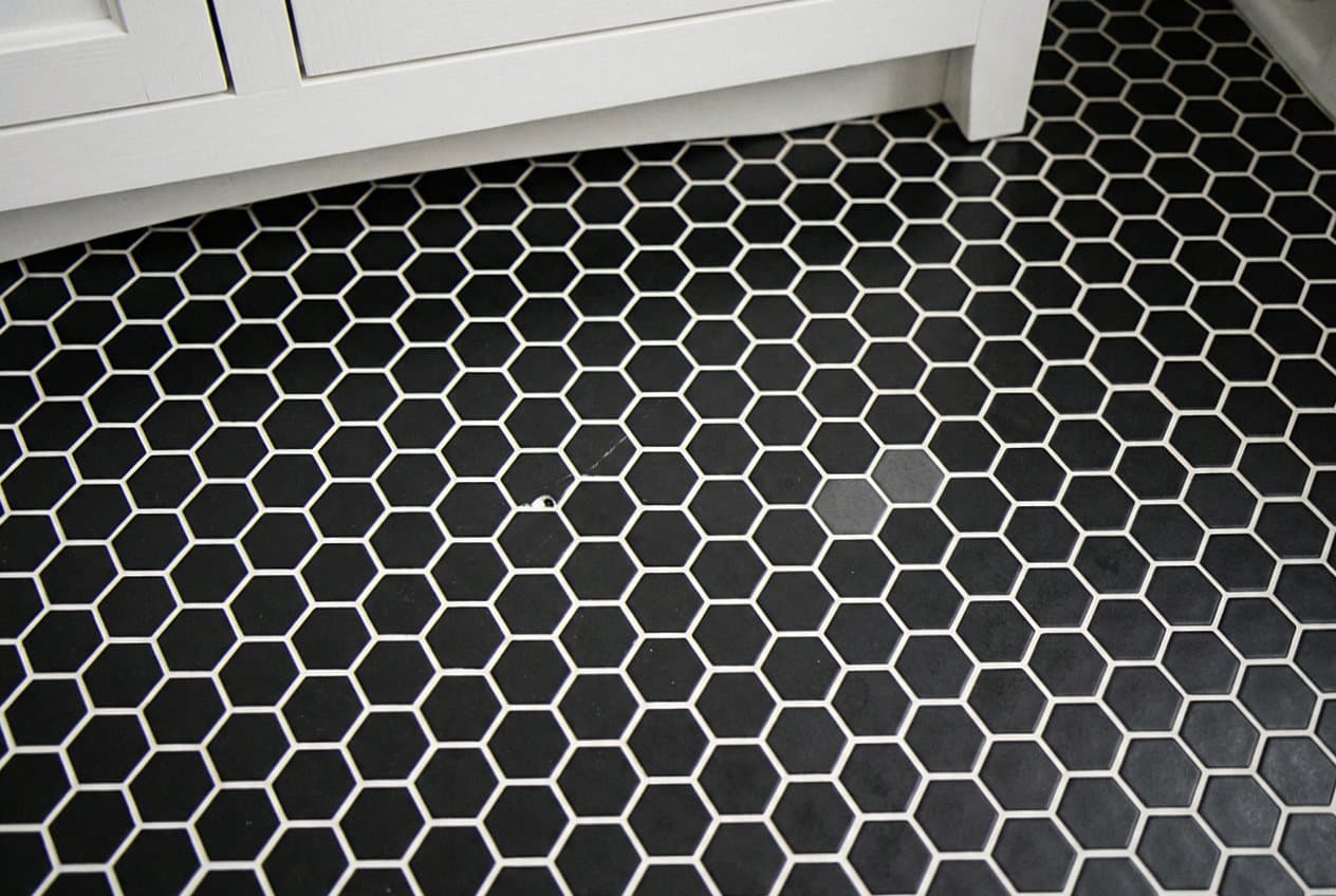 Black hexagon mosaic floor tile beside a white vanity
