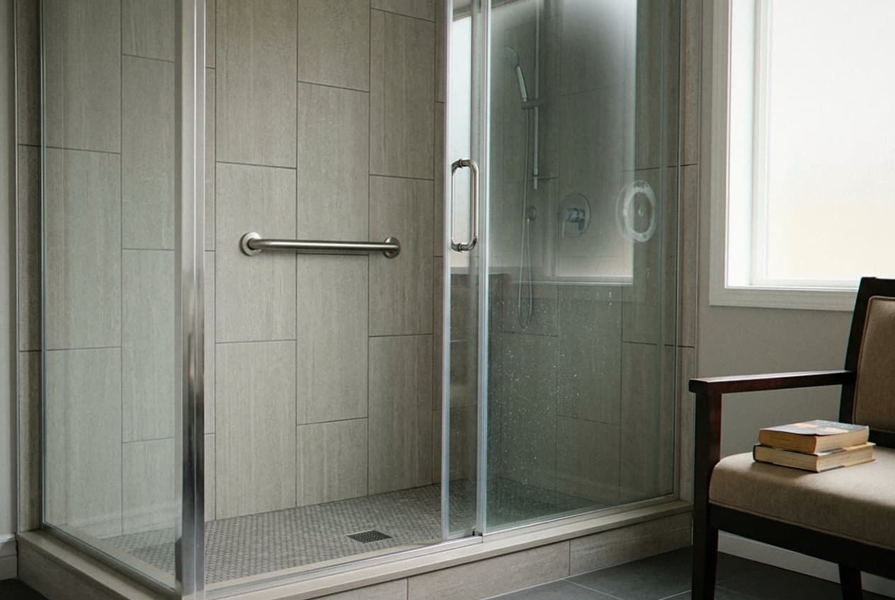 Frameless glass shower with tile walls and grab bar