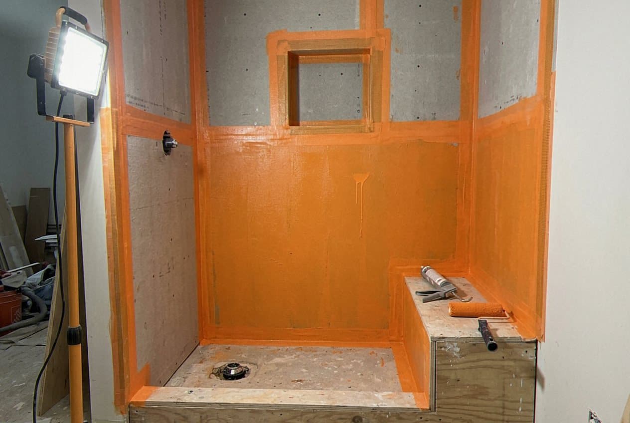 Orange waterproofing membrane taped across a framed shower